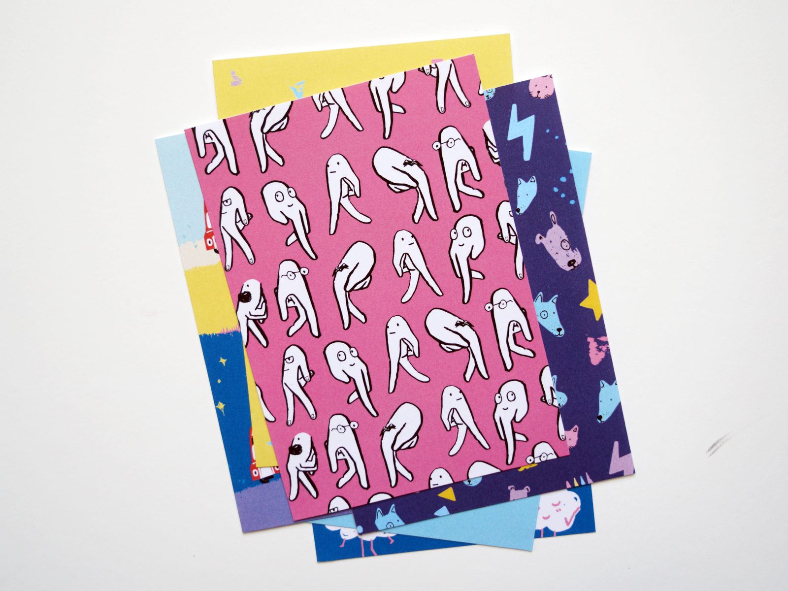 A stack of London postcards, a pink one patterned with legs on top